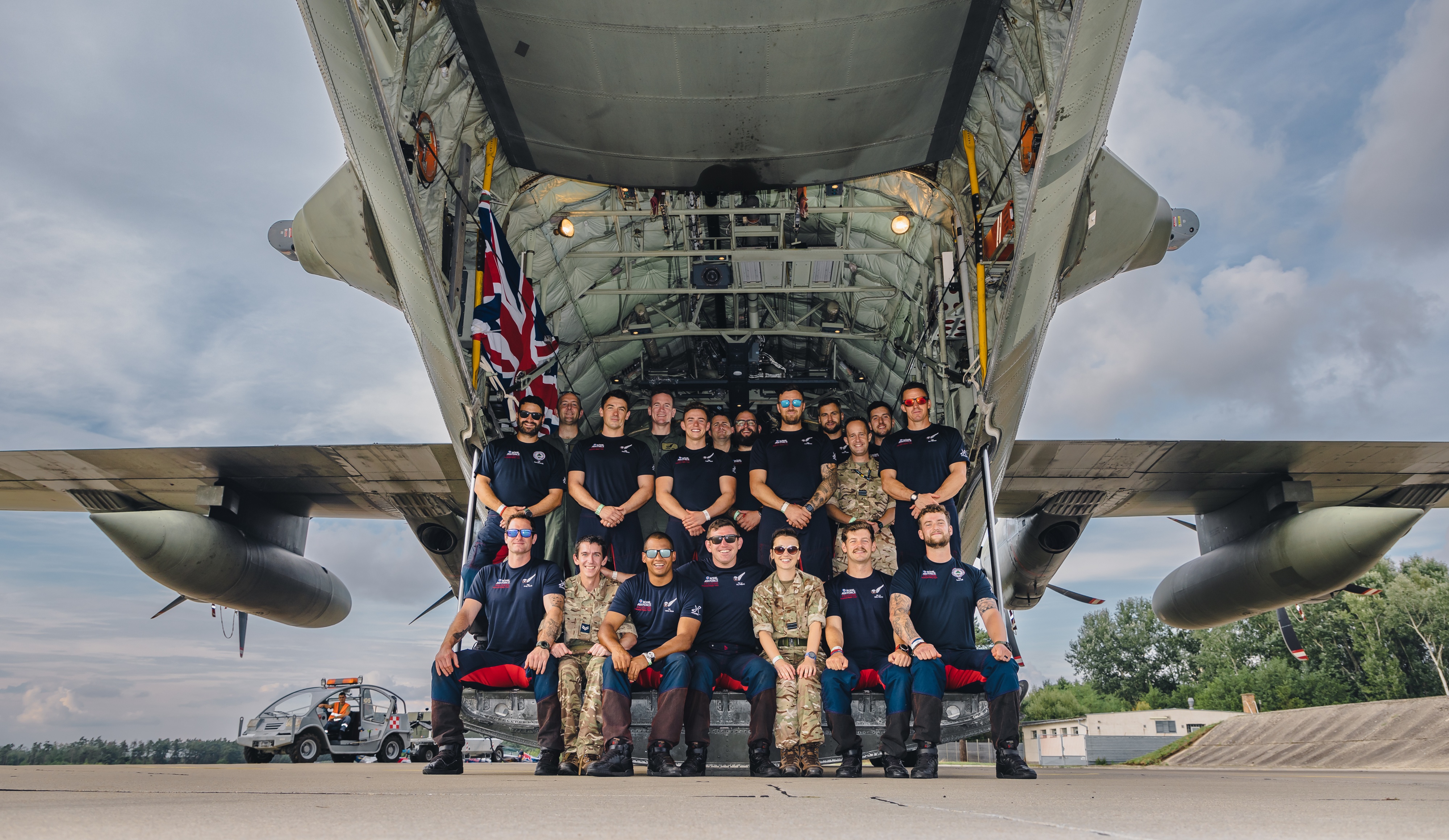 Image shows RAF aviators sitting in the loading bay of Hercules aircraft for group photo. 